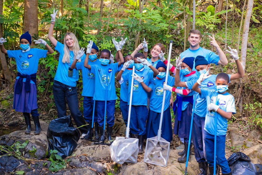 Students and volunteers cheering together with cleanup tools after a KIWI river restoration day