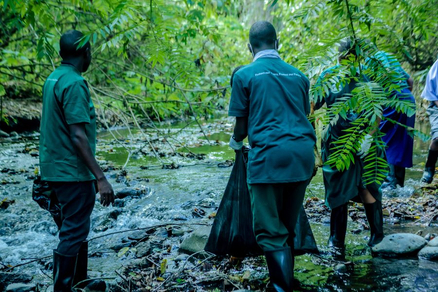 Two students carrying a waste sack along a stream during a KIWI river cleanup