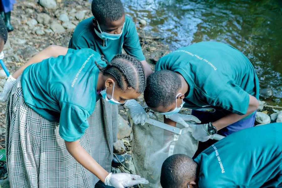 Students in gloves filling a sack with waste collected from the riverbank