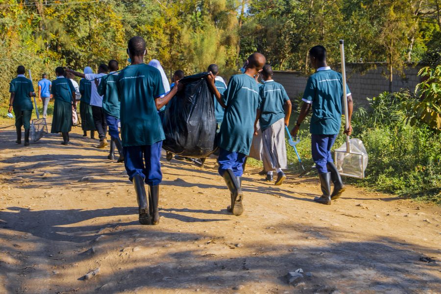 Students walking back along the path carrying bags of waste after a river cleanup